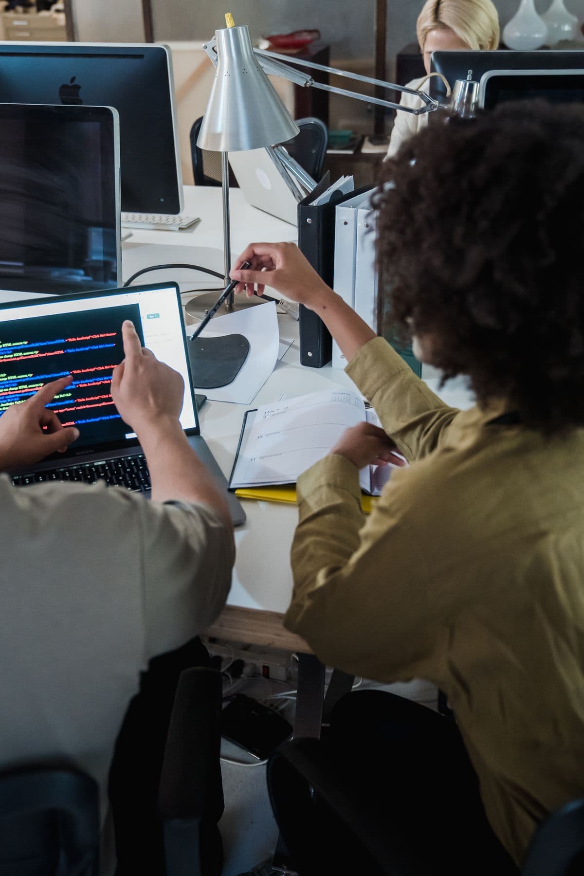 Software professionals discussing code and product details at a workstation